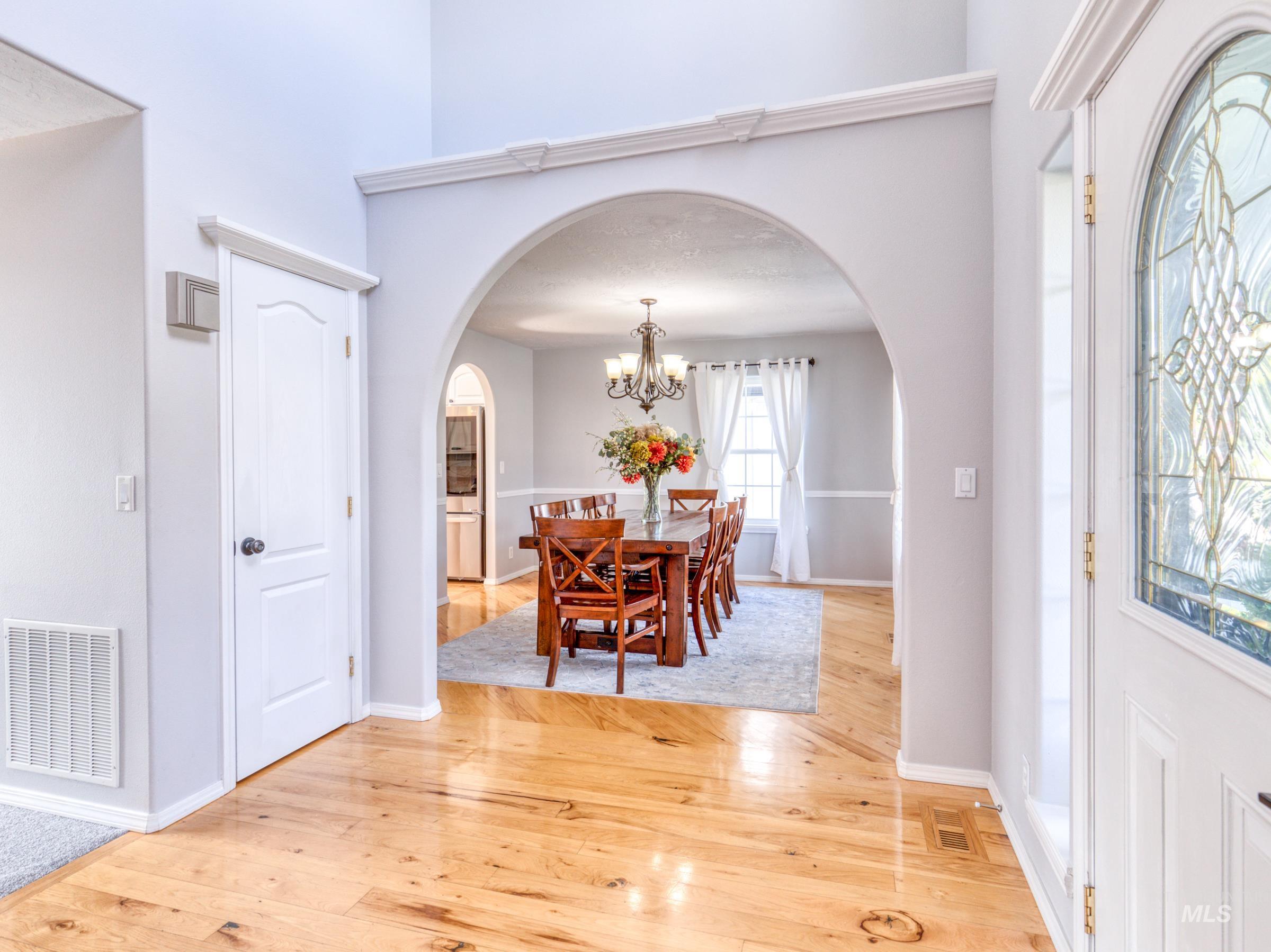 Entryway with light wood-style floors, a chandelier, and arched walkways