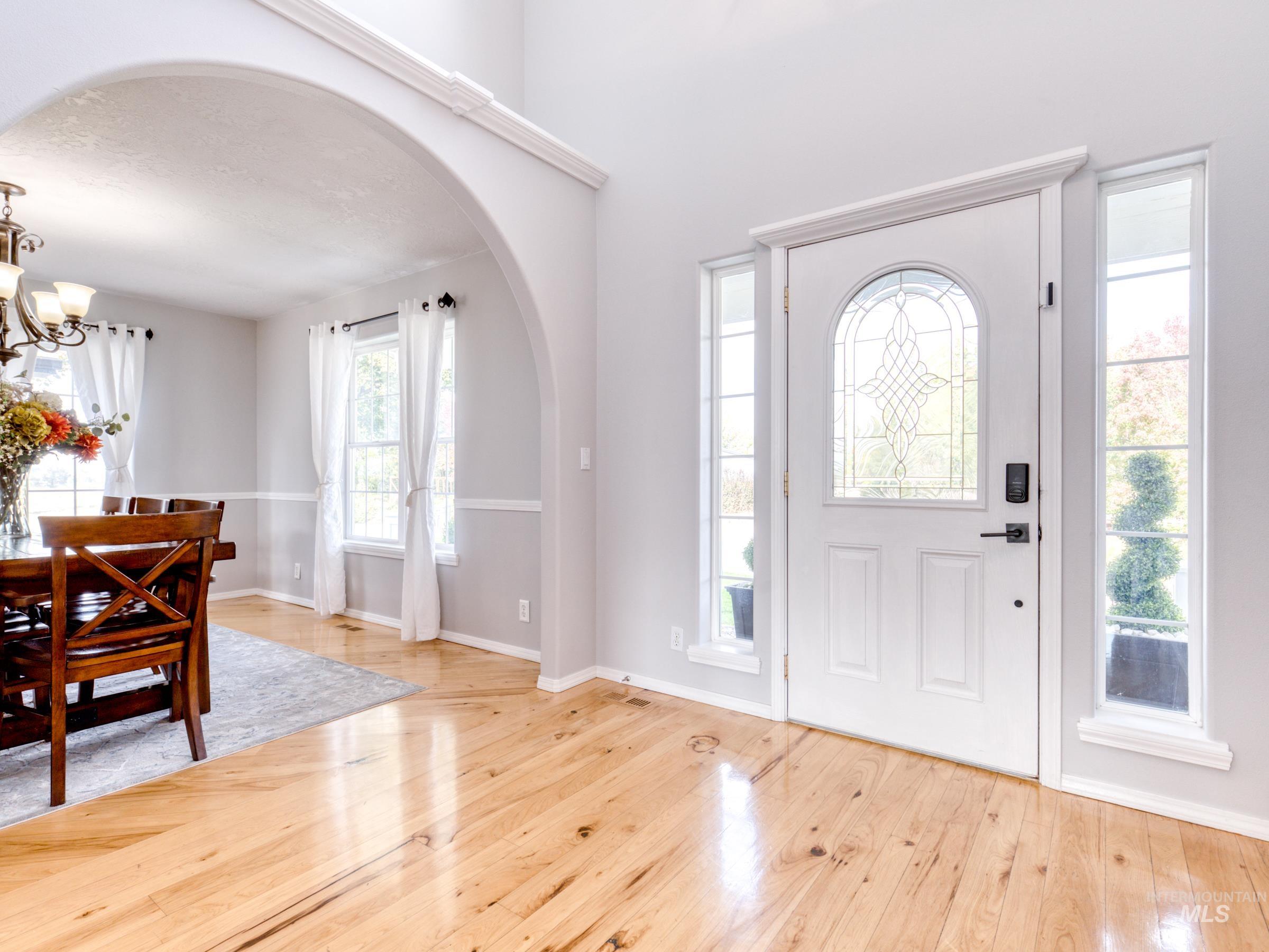 Entrance foyer featuring arched walkways, plenty of natural light, and light wood-type flooring