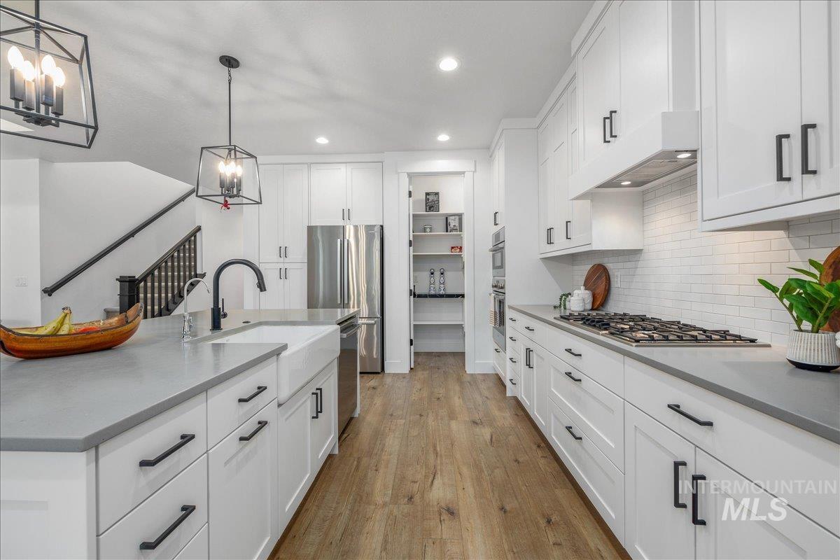 Kitchen featuring recessed lighting, decorative light fixtures, light wood-style flooring, white cabinets, and tasteful backsplash