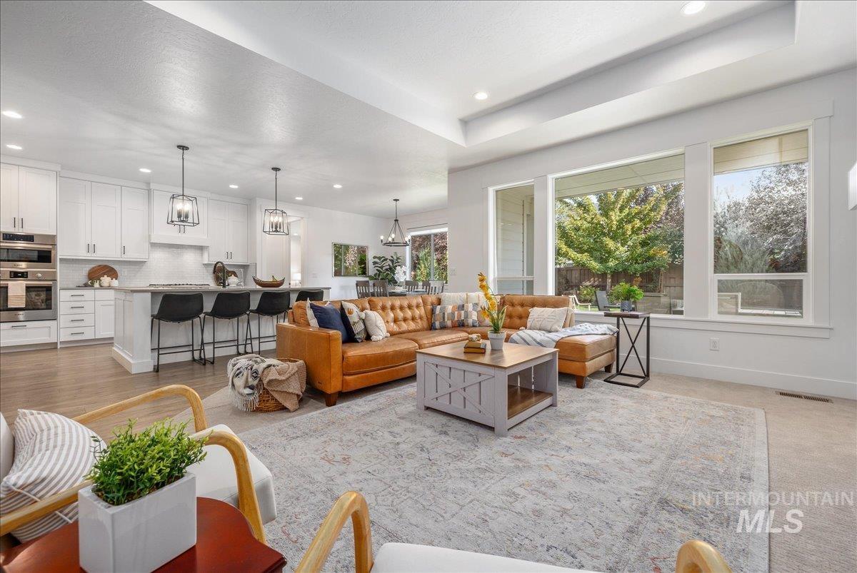 Living area featuring recessed lighting, a chandelier, a raised ceiling, and light colored carpet