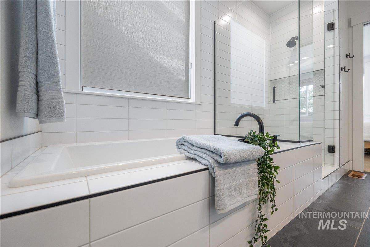 Full bathroom with a garden tub, a stall shower, plenty of natural light, and tile walls