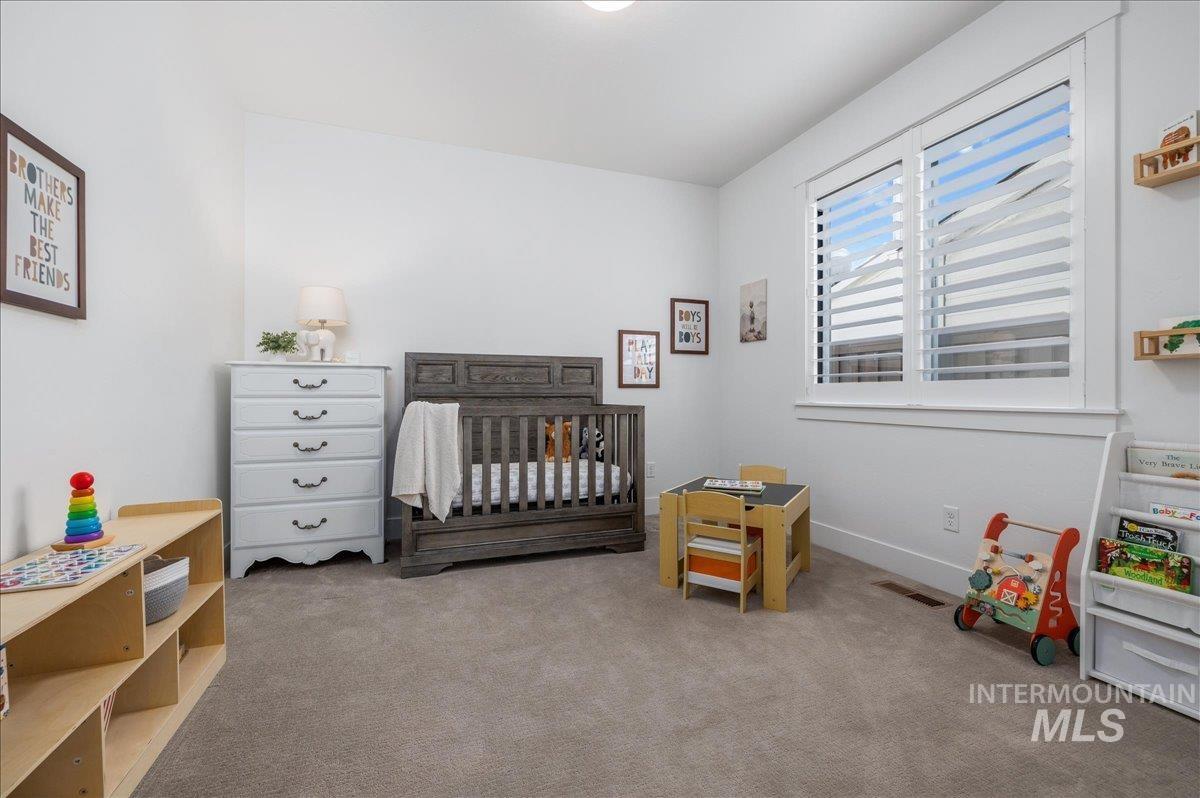Carpeted bedroom with a nursery area and baseboards