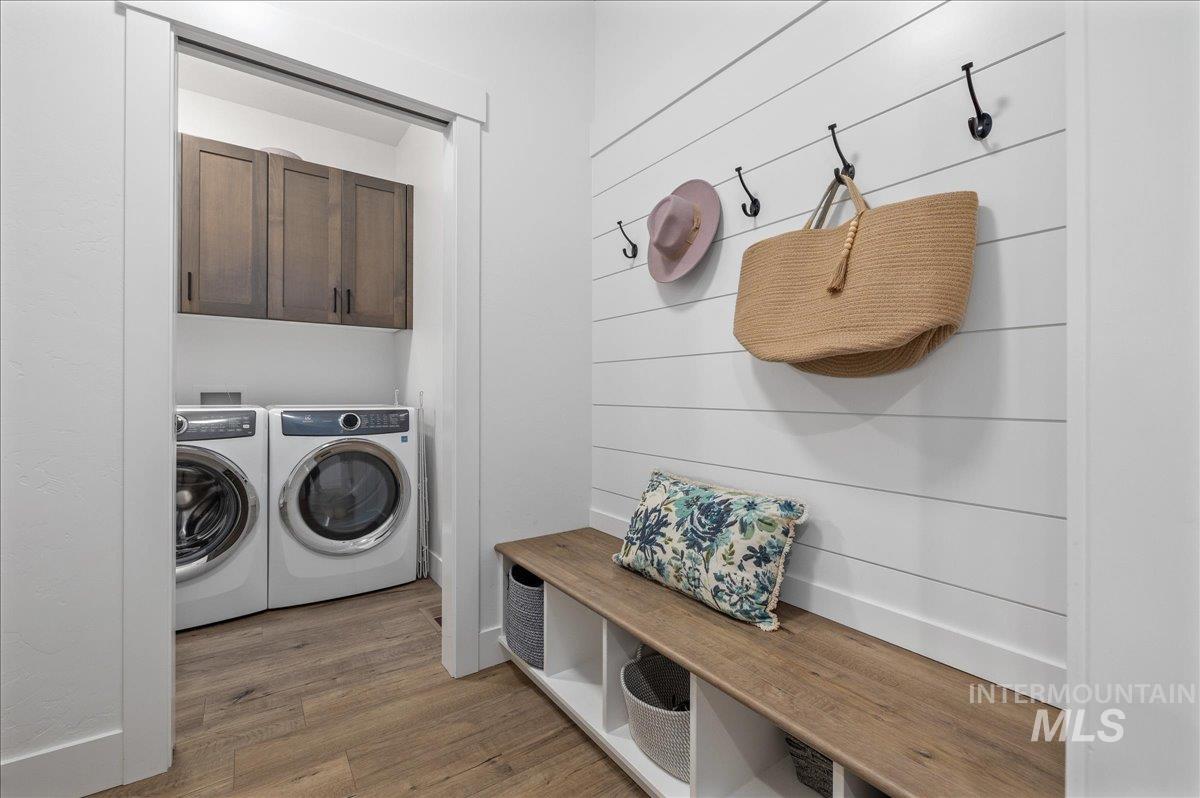Washroom with light wood-style flooring, cabinet space, and washing machine and dryer