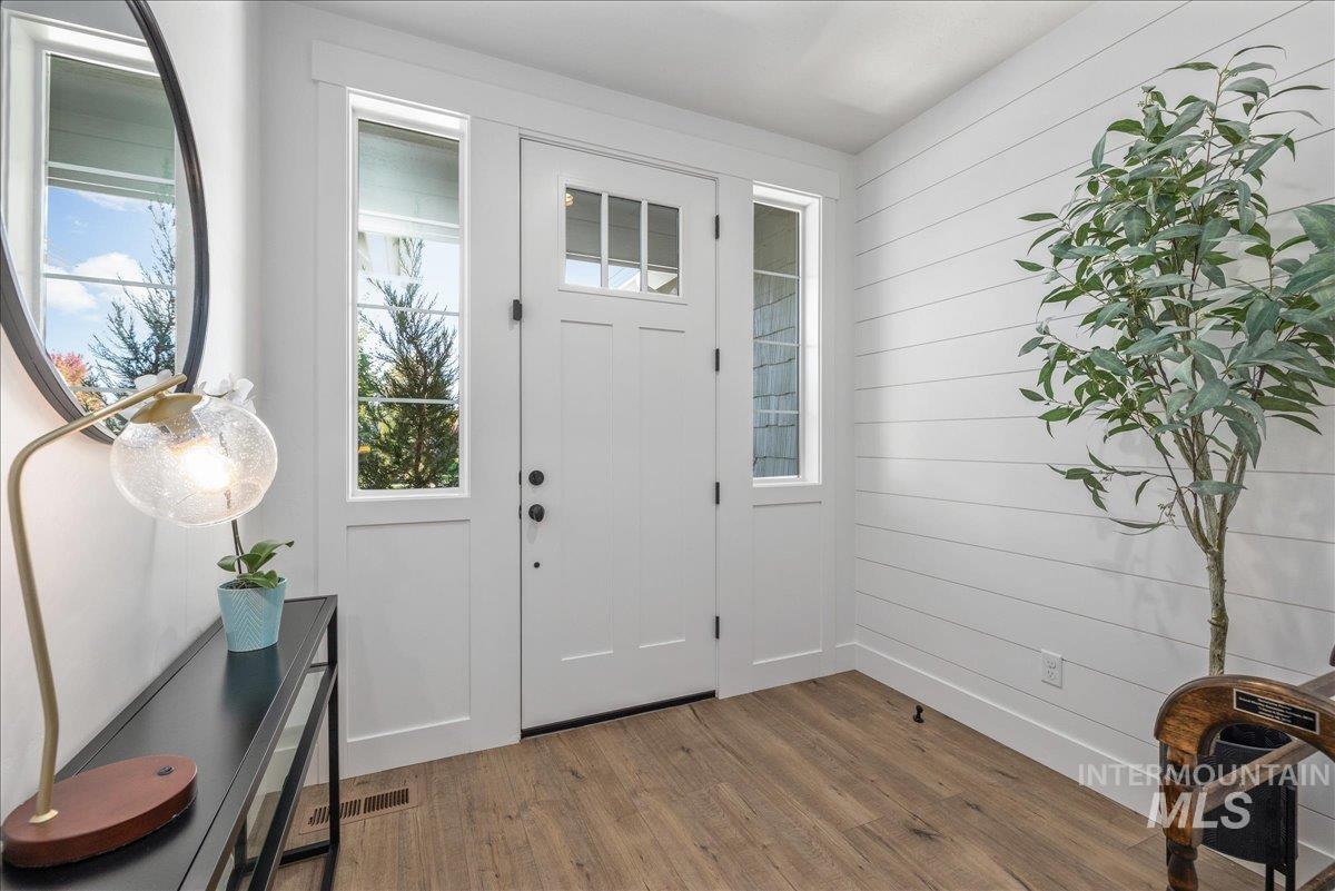 Foyer entrance featuring light wood finished floors and wood walls