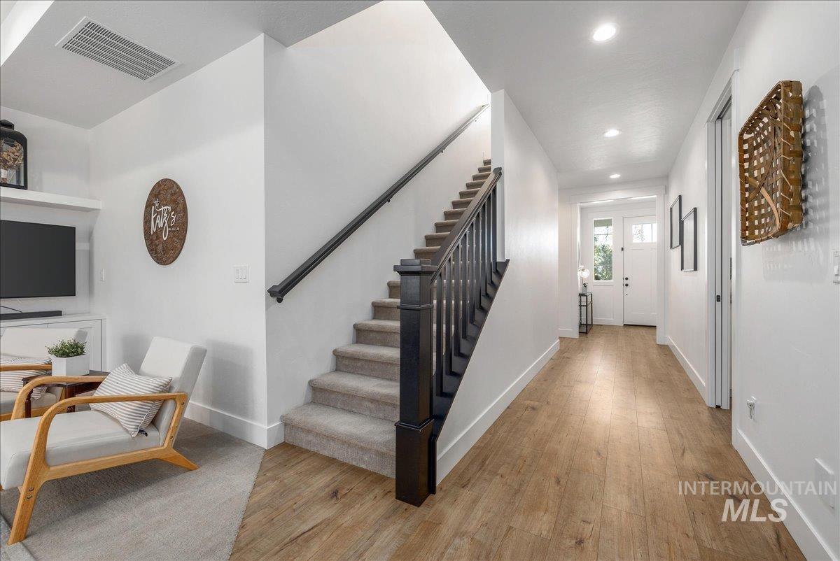 Entryway with light wood finished floors, stairway, and recessed lighting