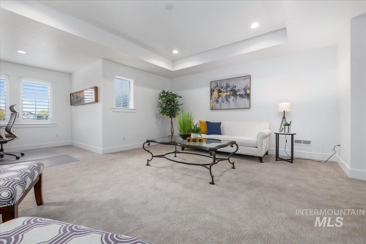 Living area featuring carpet flooring, a raised ceiling, recessed lighting, and a desk