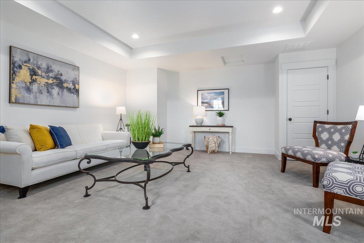 Living area featuring a tray ceiling, carpet, and recessed lighting