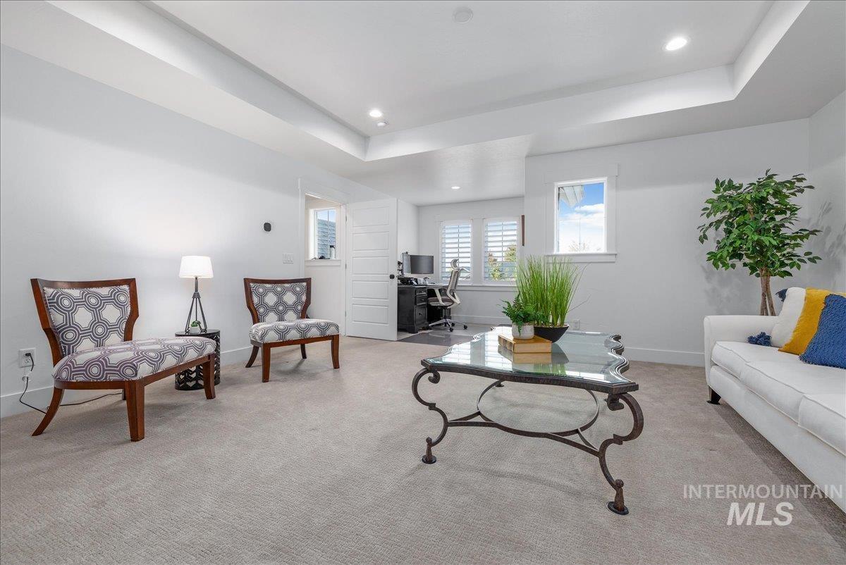 Living room featuring a tray ceiling, a desk, carpet, and recessed lighting