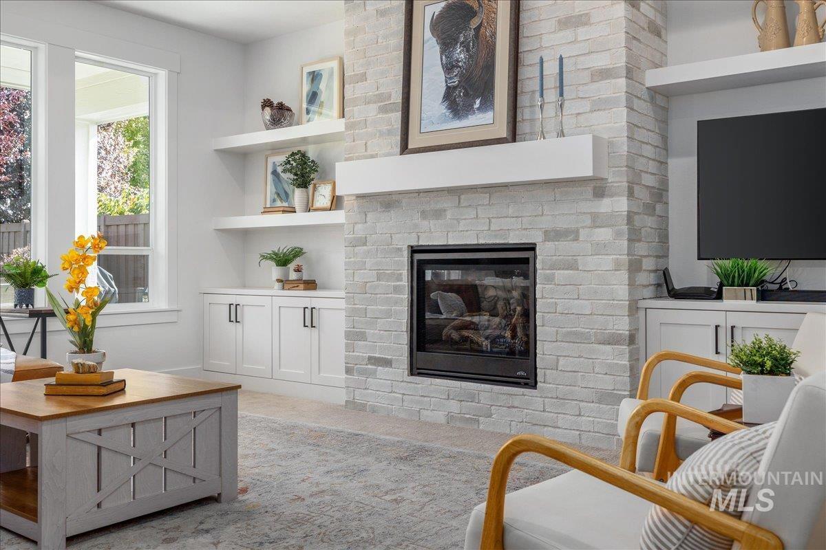 Living area featuring a fireplace, light carpet, and built in shelves