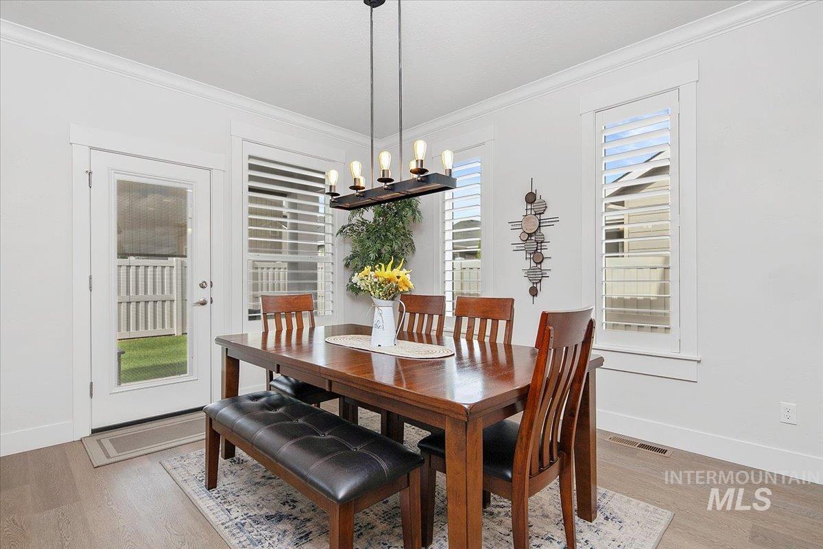 Dining space featuring crown molding, light wood-style floors, and a chandelier