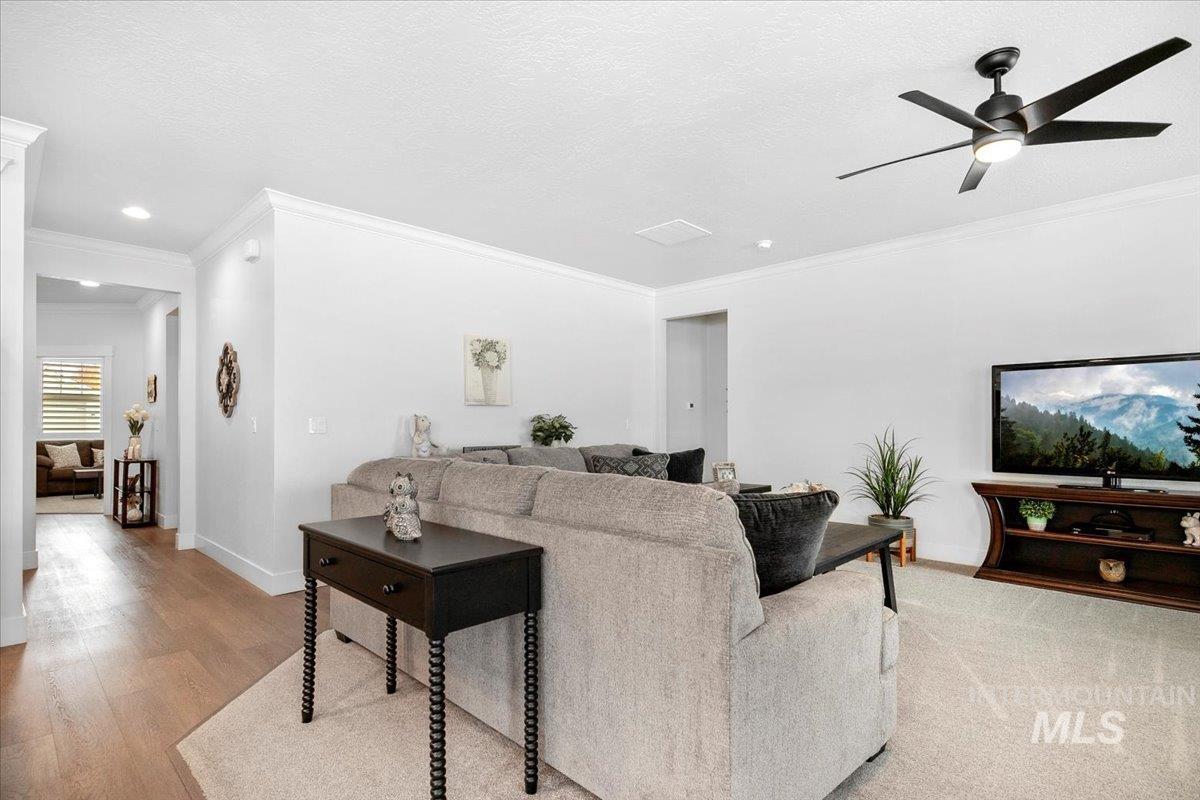 Living room featuring crown molding, a ceiling fan, a textured ceiling, and light wood-style flooring