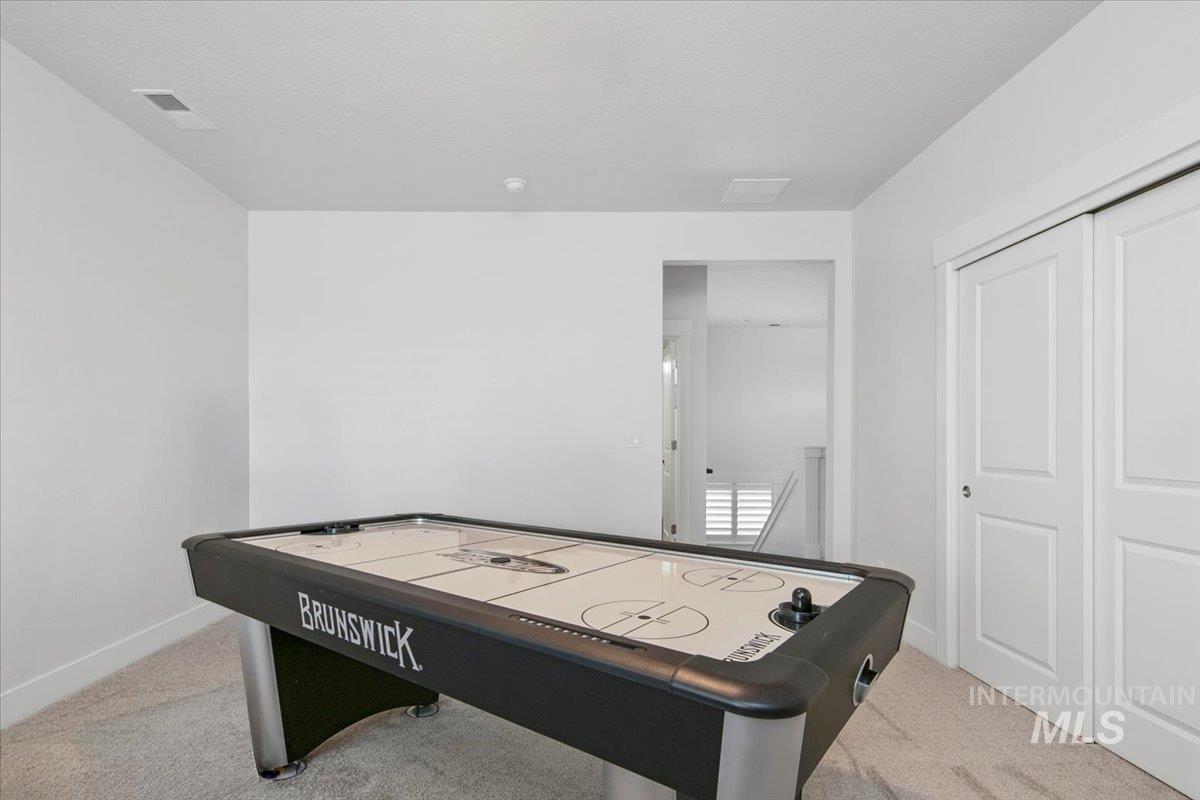 Game room with light carpet and baseboards