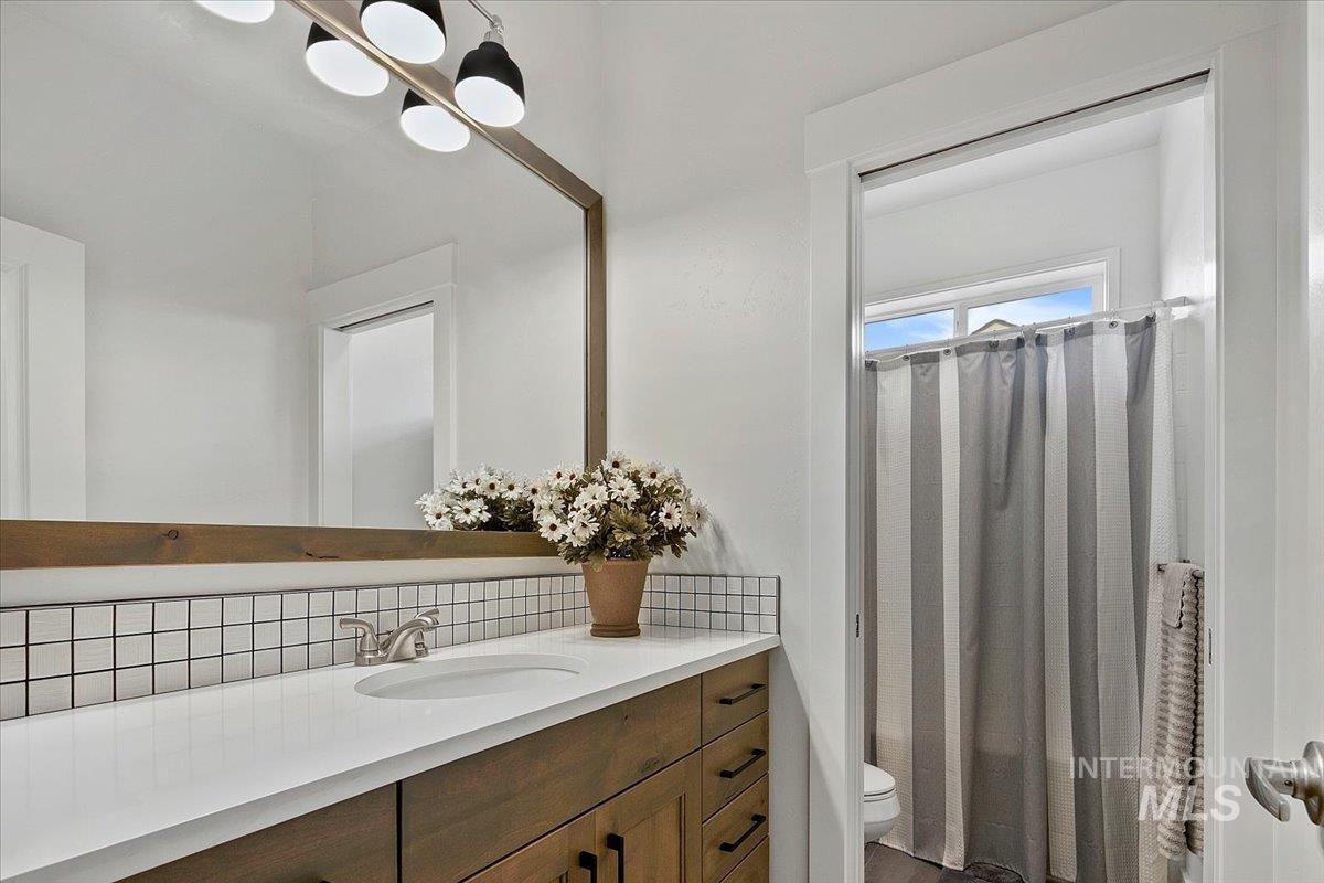 Full bathroom featuring vanity and tasteful backsplash