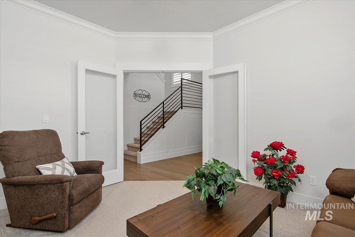 Living room with crown molding and stairway