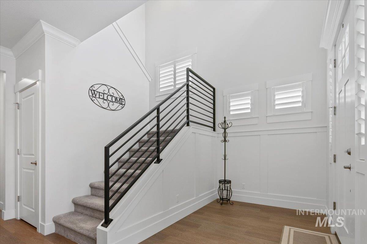 Stairs featuring wood finished floors and ornamental molding