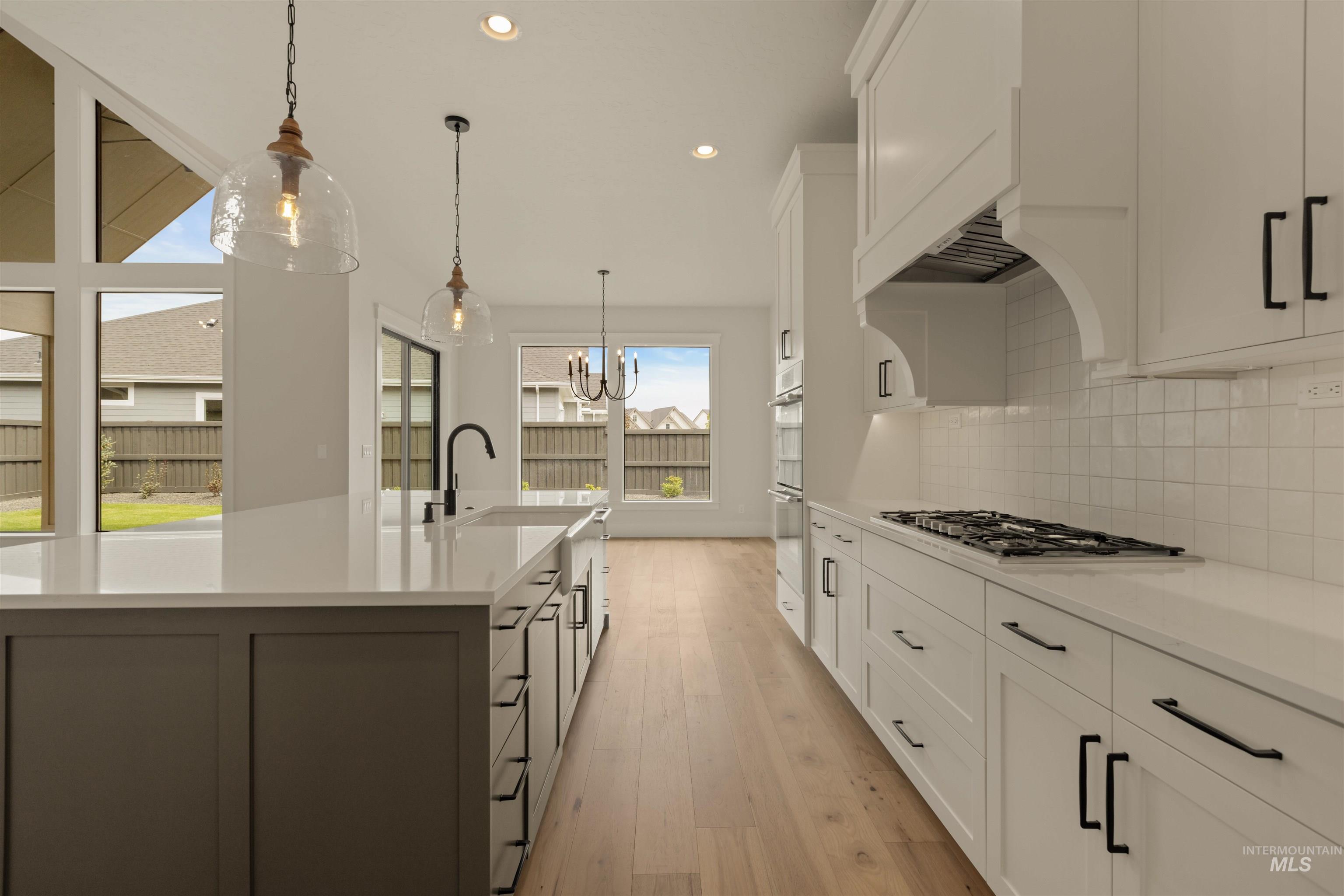 Kitchen with recessed lighting, white cabinets, hanging light fixtures, light wood-style floors, and a chandelier