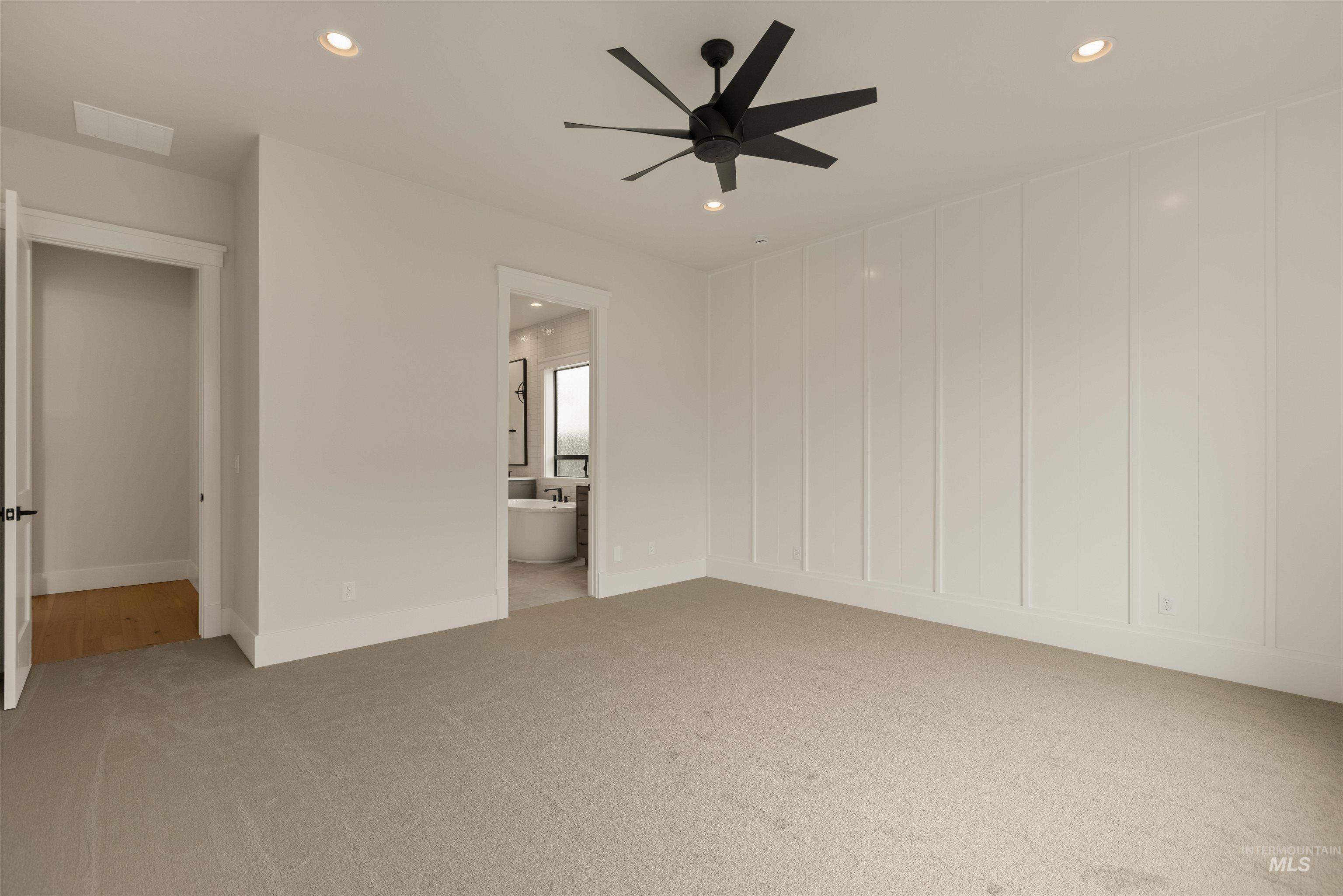 Unfurnished bedroom with recessed lighting, light colored carpet, ceiling fan, ensuite bathroom, and a decorative wall
