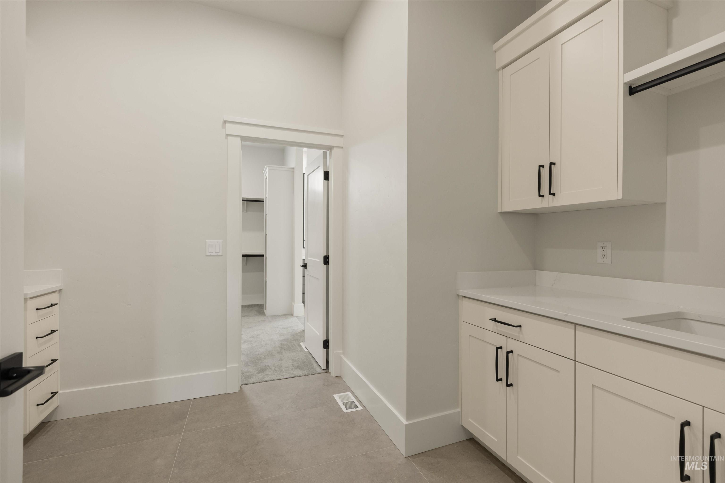 Bar area featuring white cabinets, light stone countertops, and light tile patterned floors