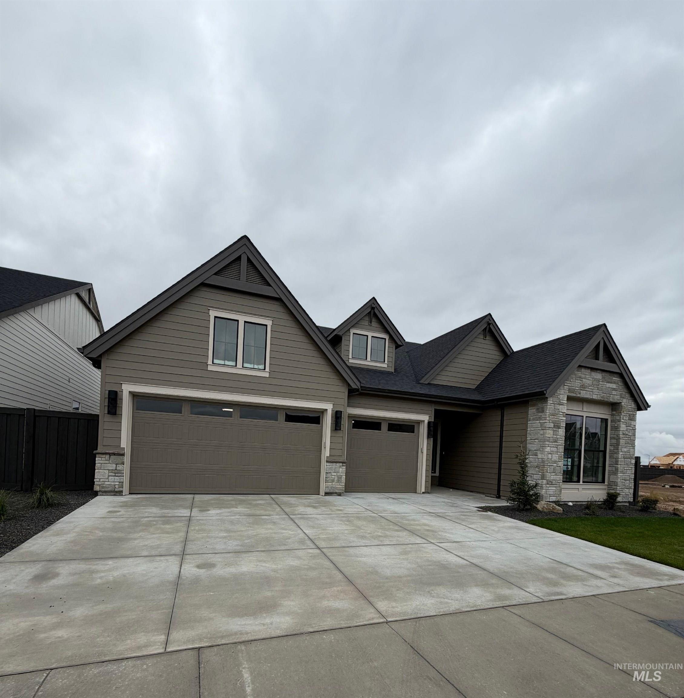 Craftsman house with stone siding, driveway, and an attached garage