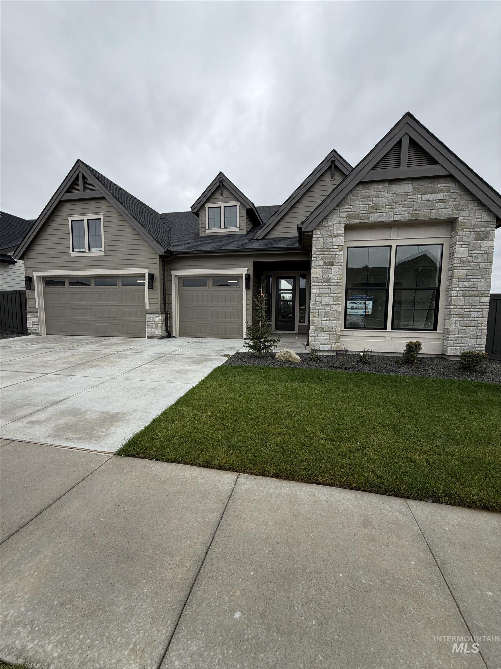 Craftsman-style house featuring stone siding, a front lawn, concrete driveway, and a garage