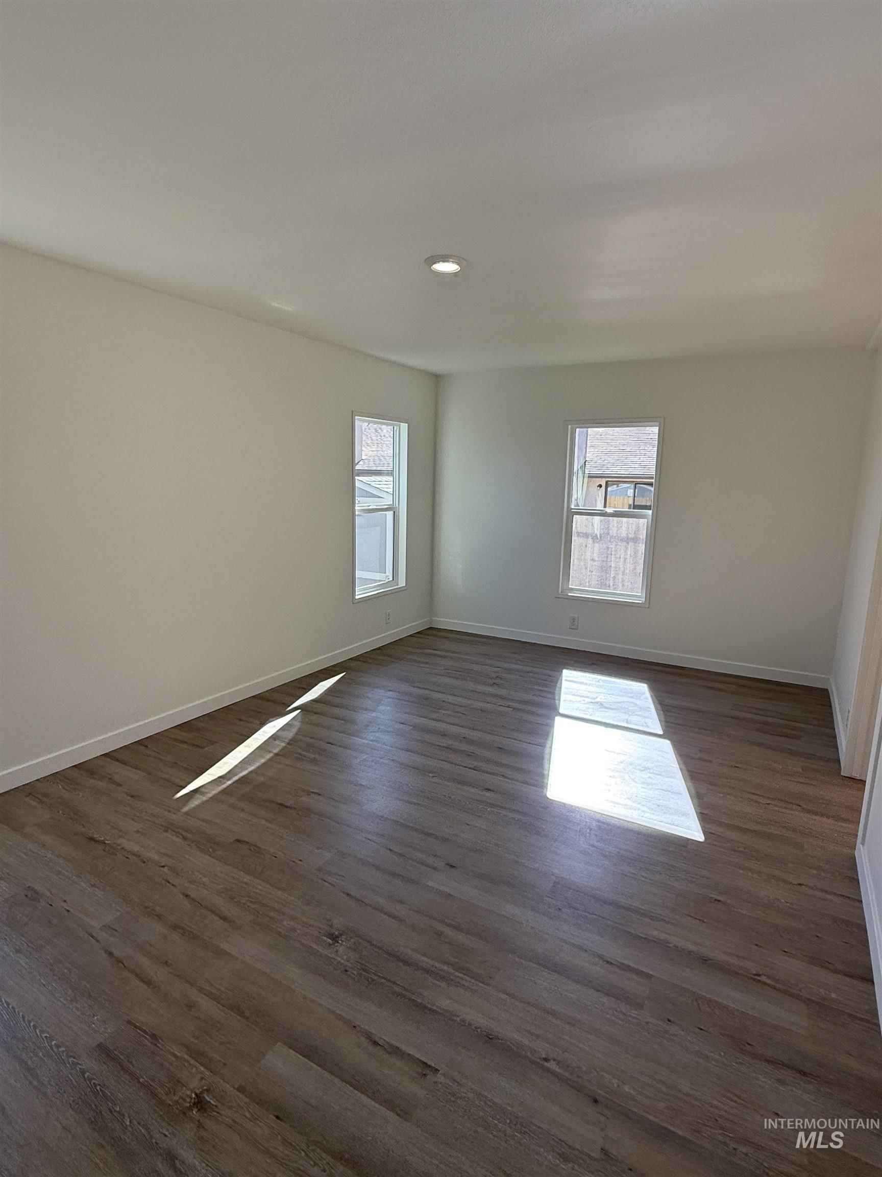 Spare room with plenty of natural light, dark wood-style flooring, and recessed lighting