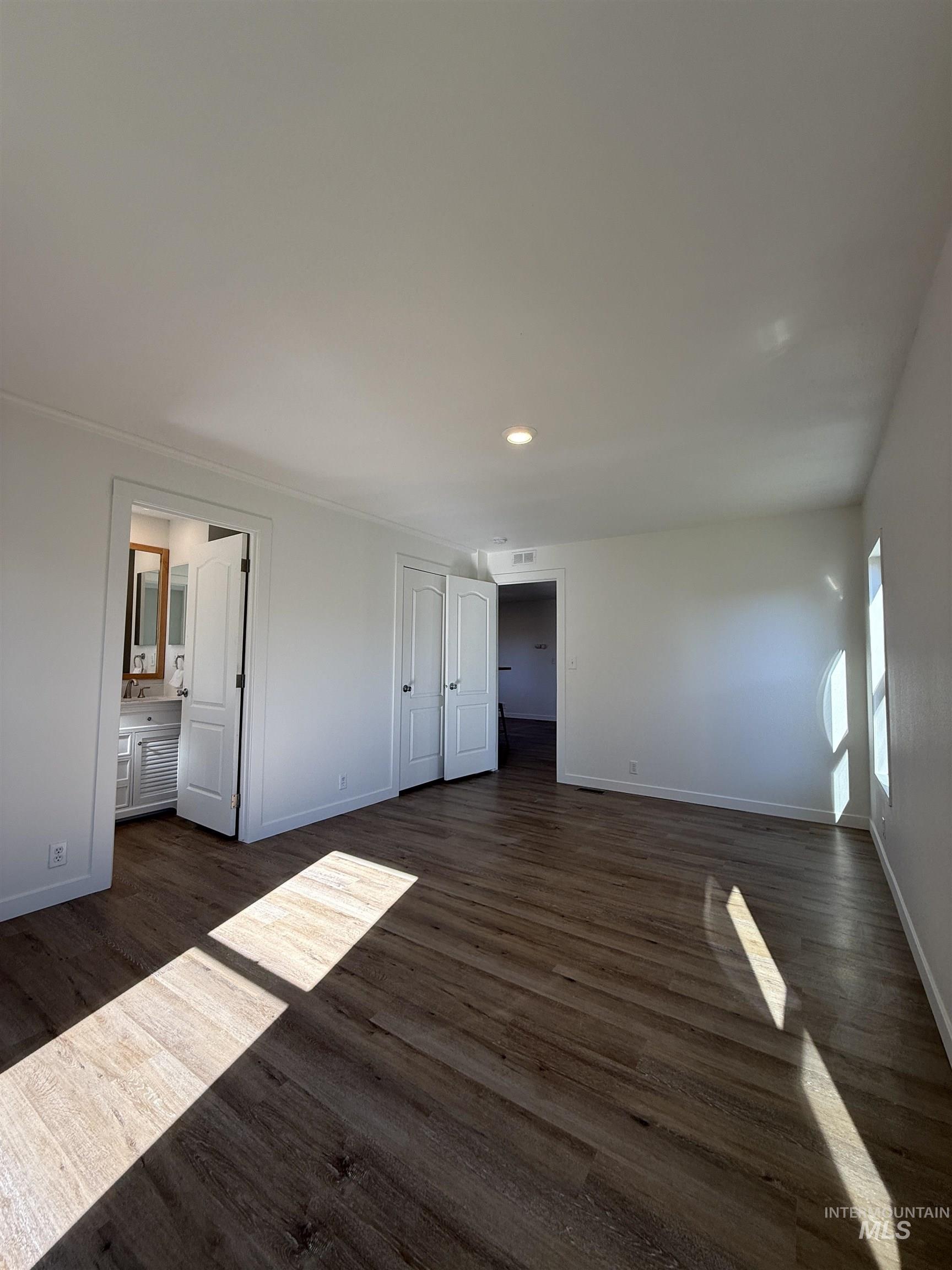 Unfurnished bedroom featuring dark wood-type flooring, recessed lighting, and ensuite bath