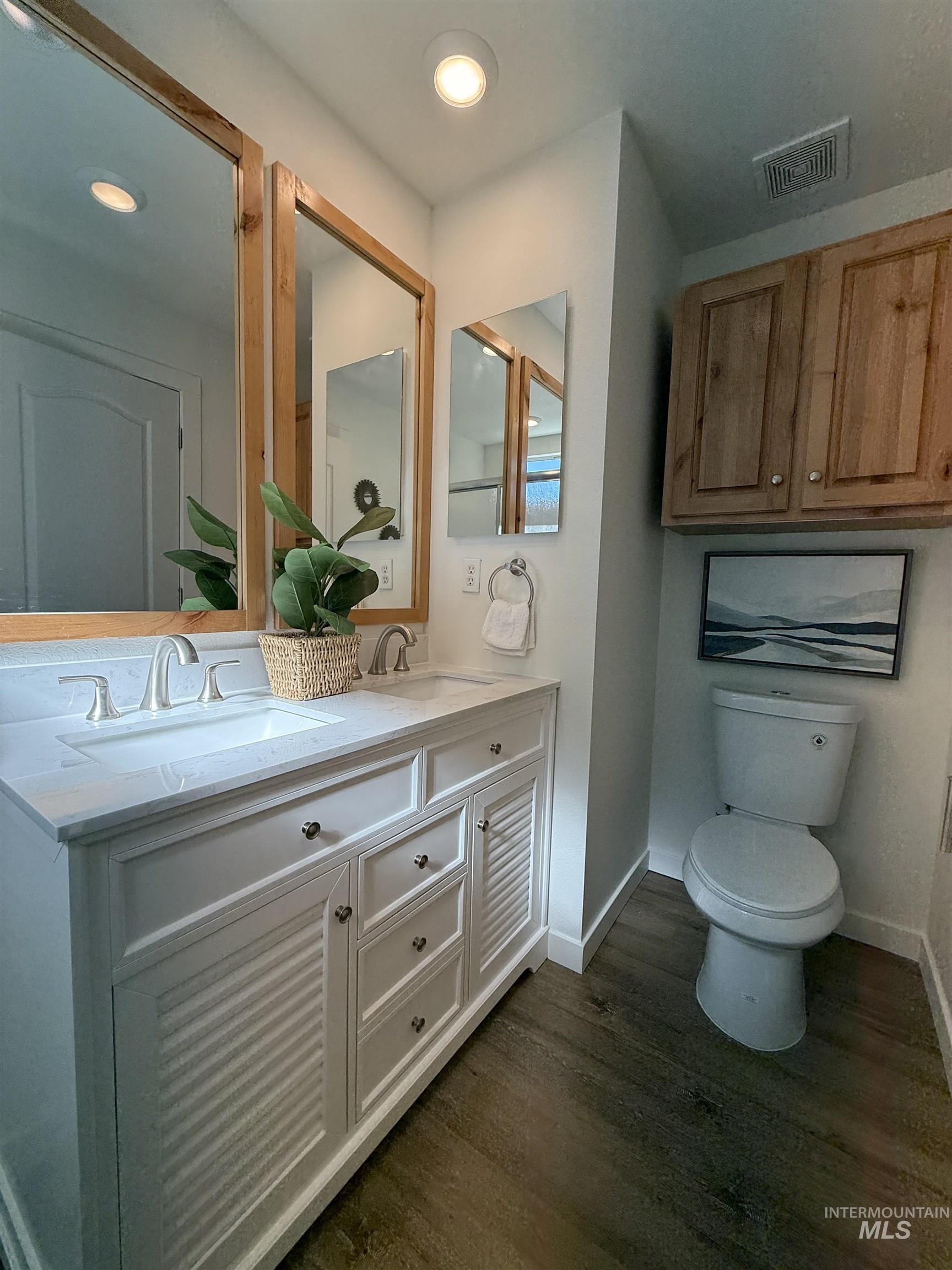 Bathroom featuring dark wood-style flooring and double vanity