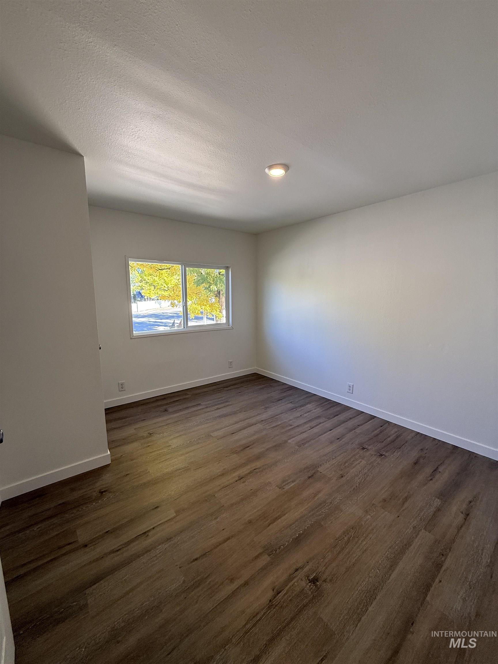 Spare room with dark wood-style floors and a textured ceiling