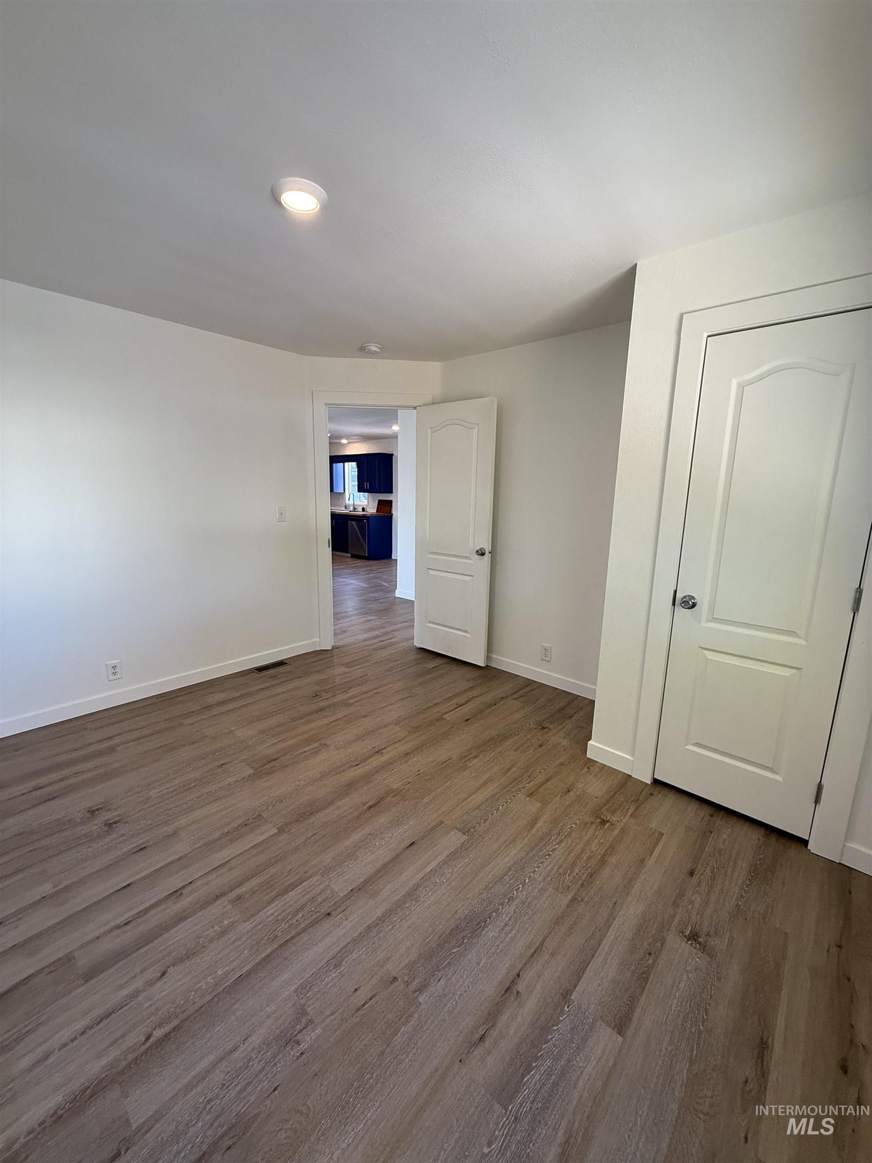 Spare room featuring dark wood-style floors and baseboards