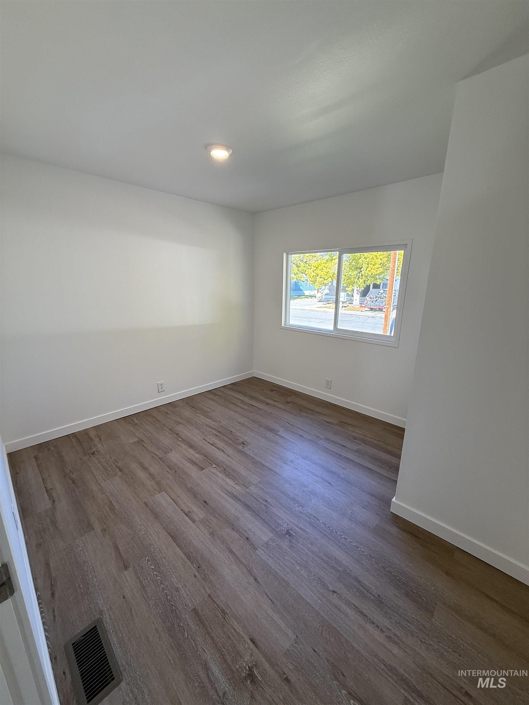 Spare room featuring dark wood finished floors and baseboards