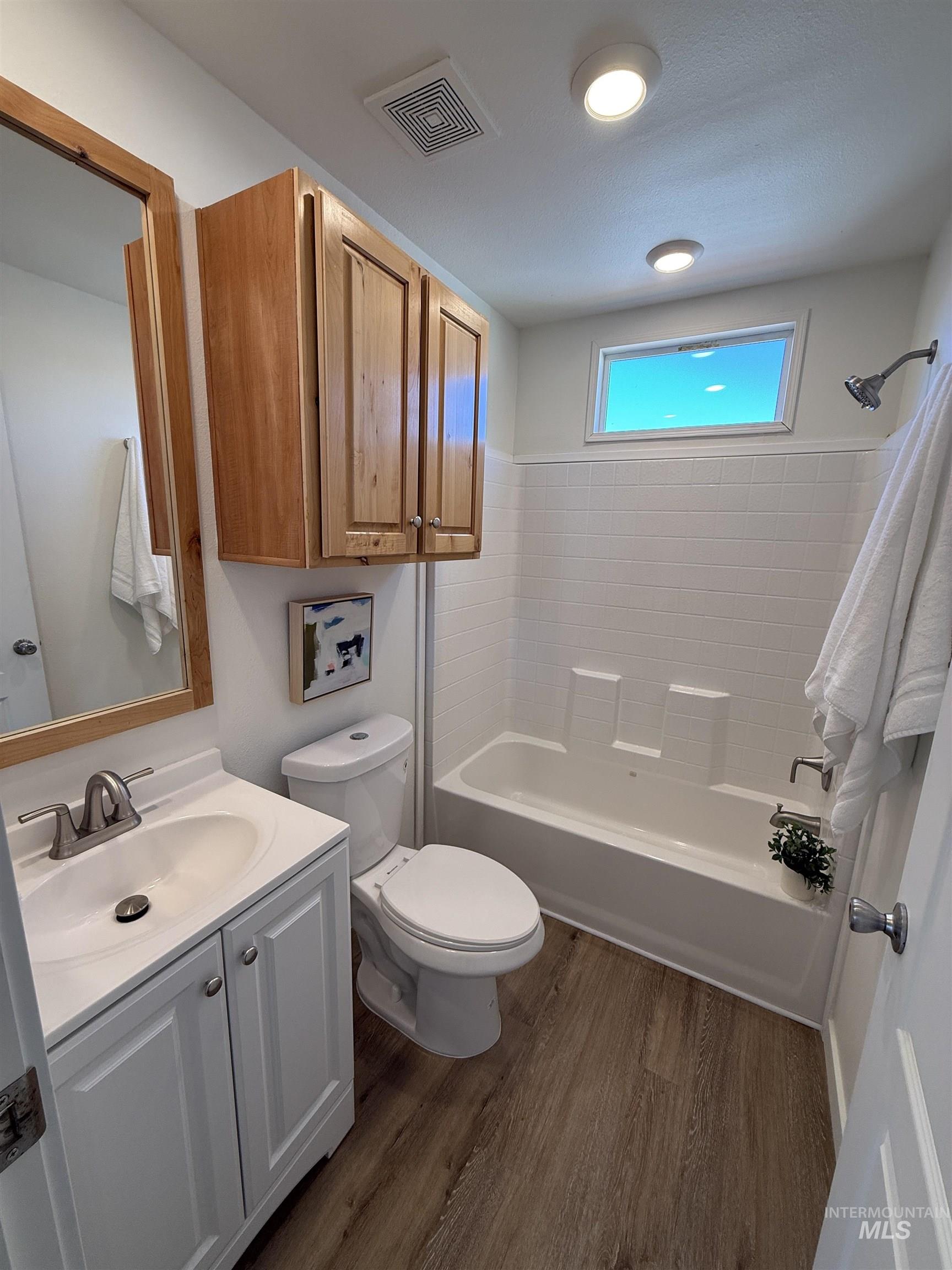 Bathroom with vanity, dark wood-style floors, and bathtub / shower combination