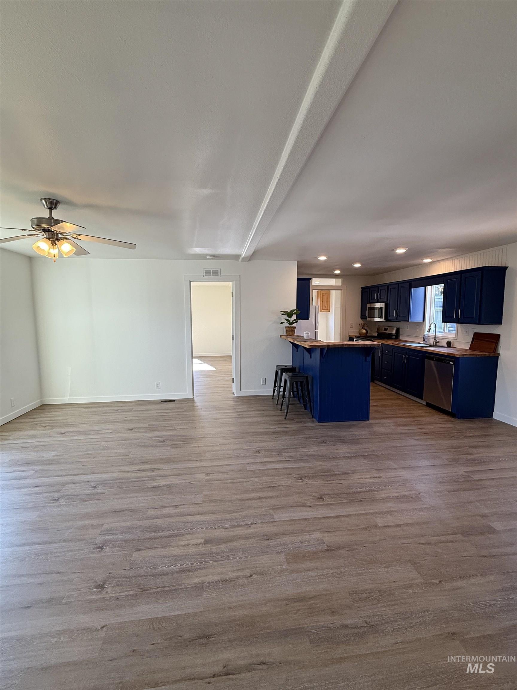 Kitchen featuring blue cabinetry, a breakfast bar area, a peninsula, dark wood finished floors, and recessed lighting