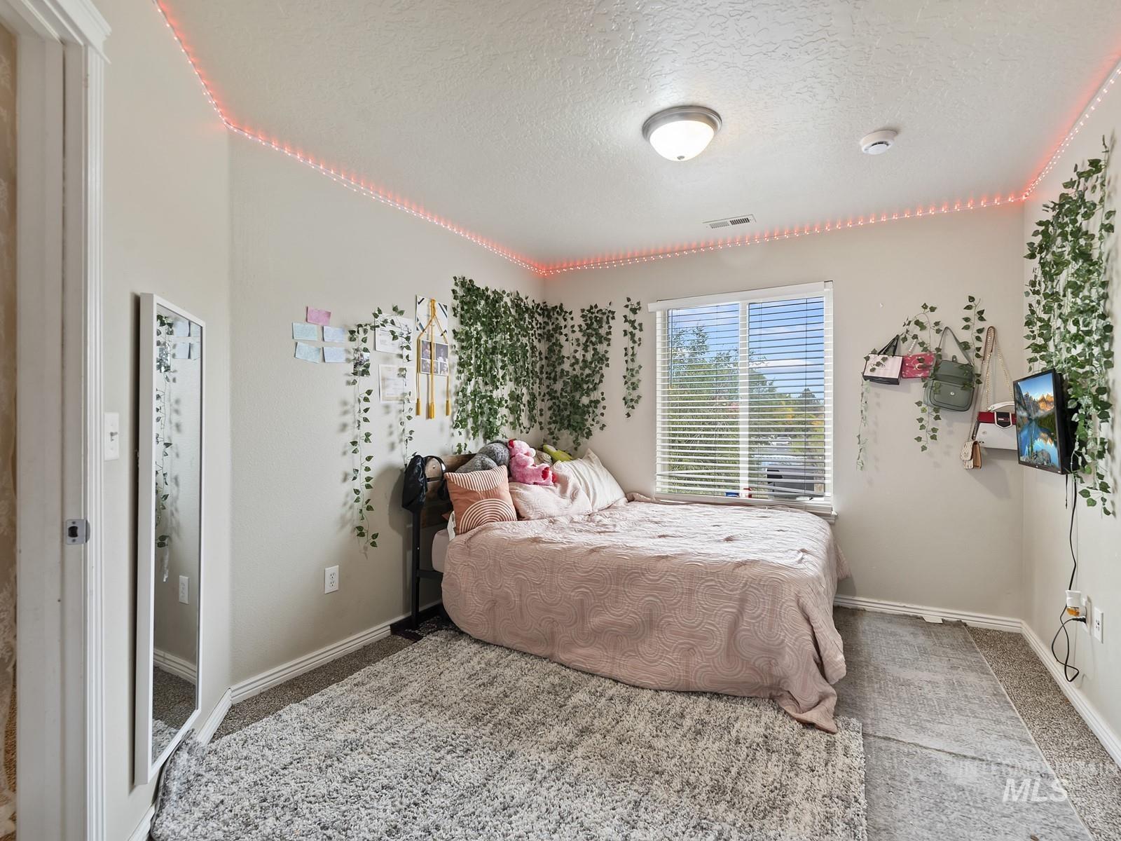 Carpeted bedroom featuring a textured ceiling and baseboards
