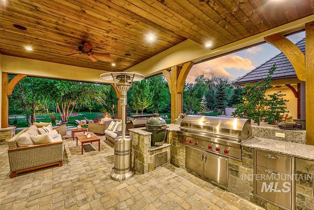 Patio terrace at dusk featuring an outdoor hangout area, an outdoor kitchen, ceiling fan, and a patio