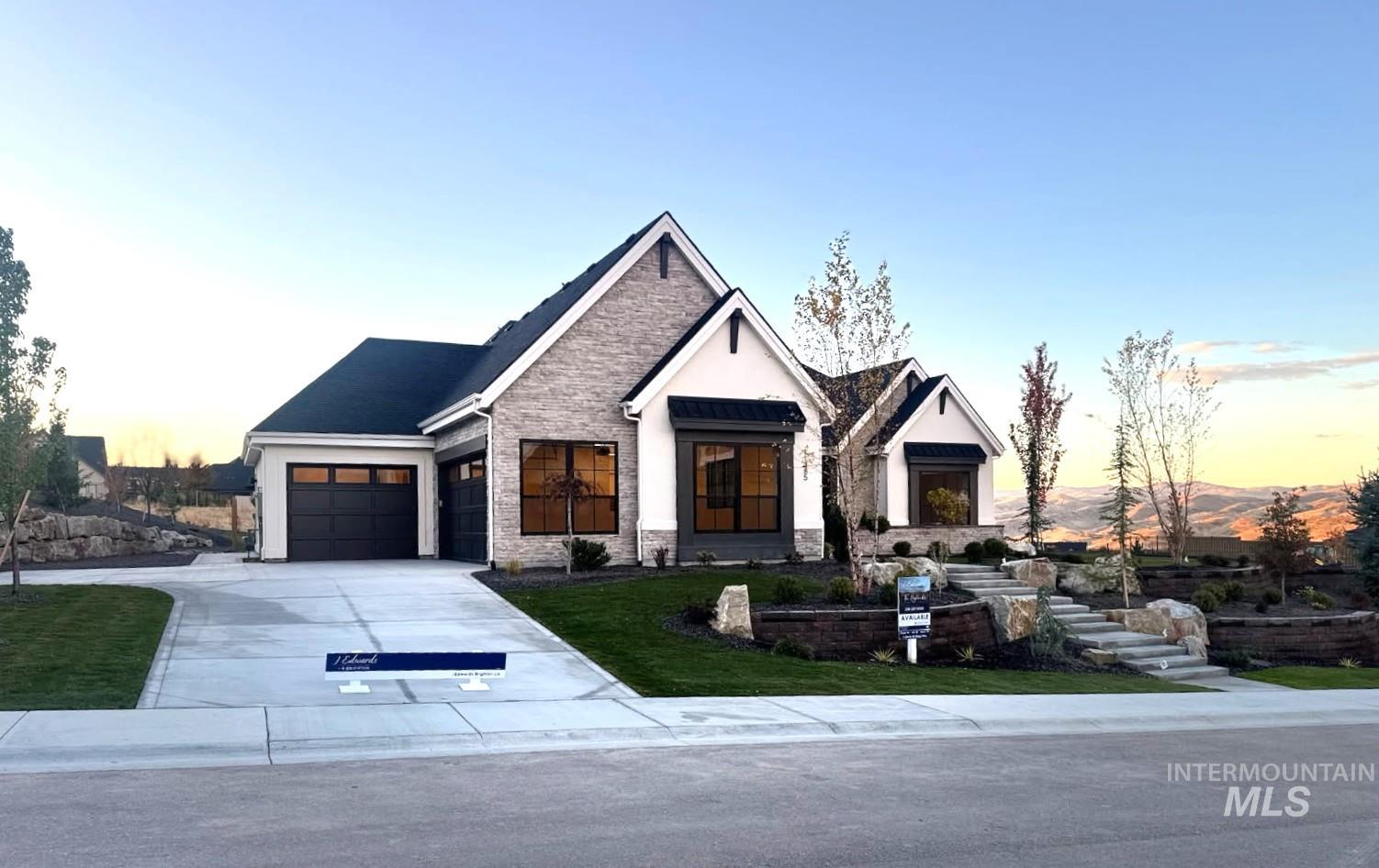 Modern farmhouse with stone siding, concrete driveway, a yard, stucco siding, and a garage