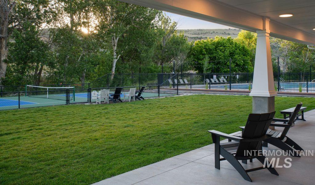 View of home's community featuring a patio, view of wooded area, and a tennis court