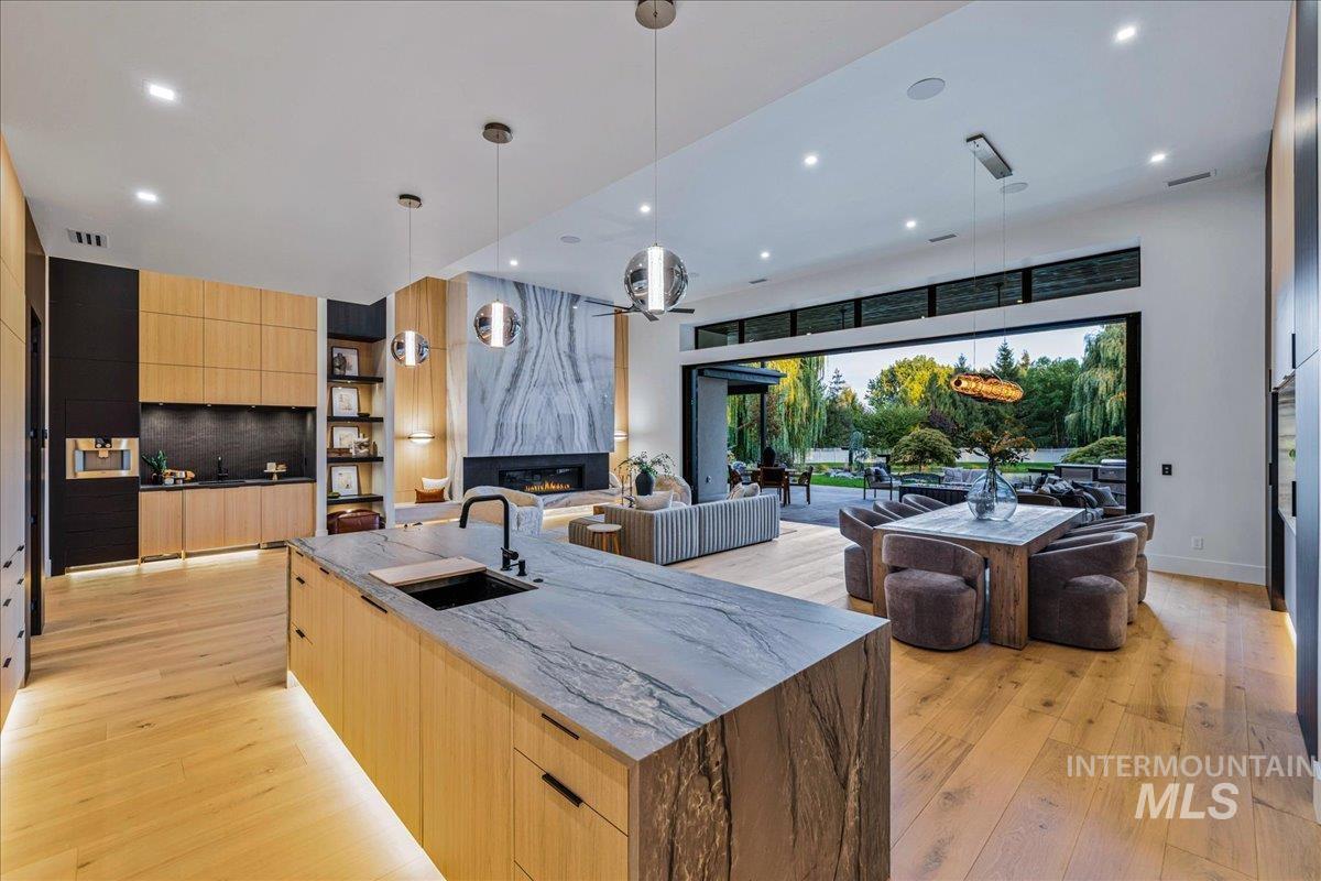 Kitchen with modern cabinets, light brown cabinets, decorative light fixtures, a premium fireplace, and recessed lighting
