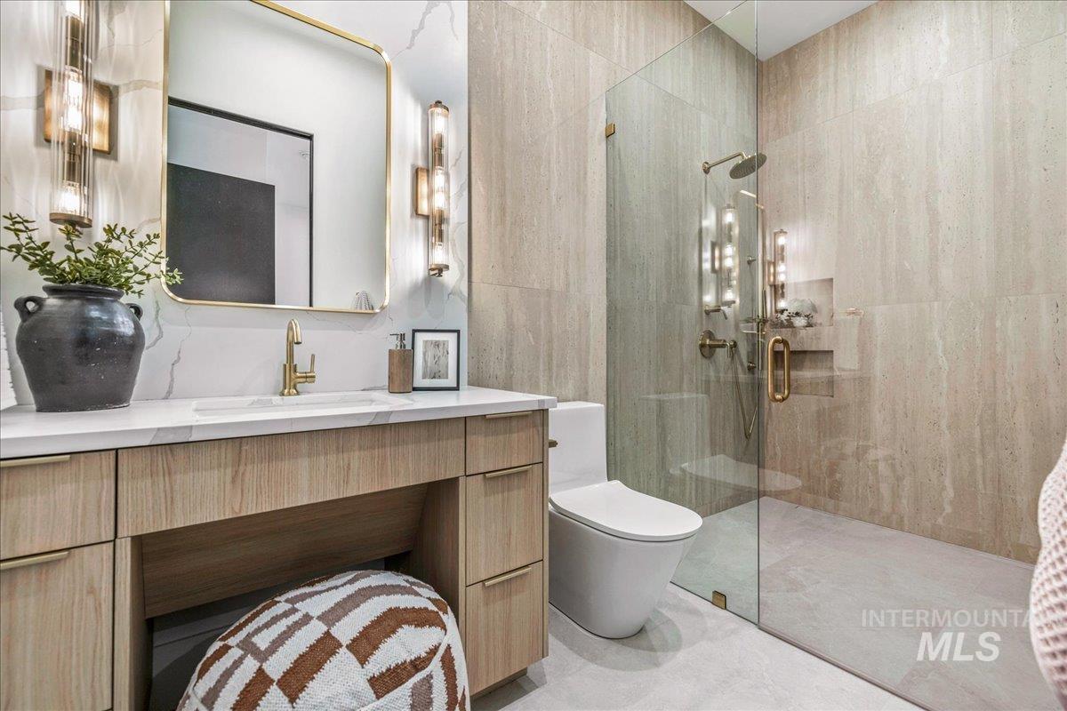 Full bath with a shower stall, vanity, and tile walls