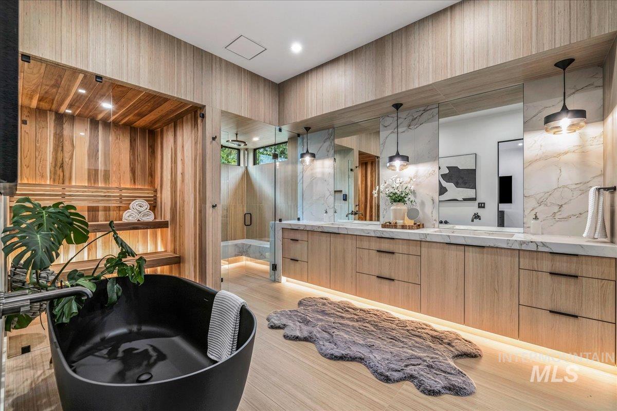 Bathroom featuring double vanity, a stall shower, light wood-style floors, and a freestanding tub