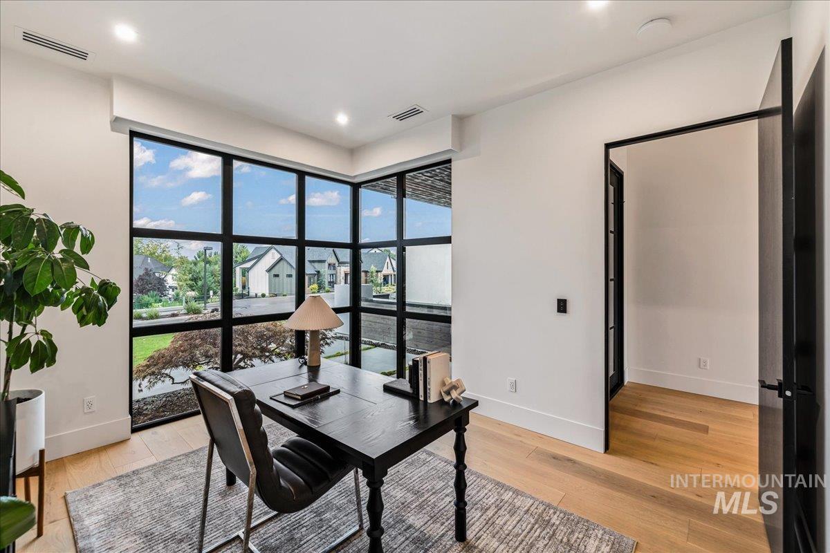 Office area featuring light wood-style flooring, recessed lighting, and a residential view