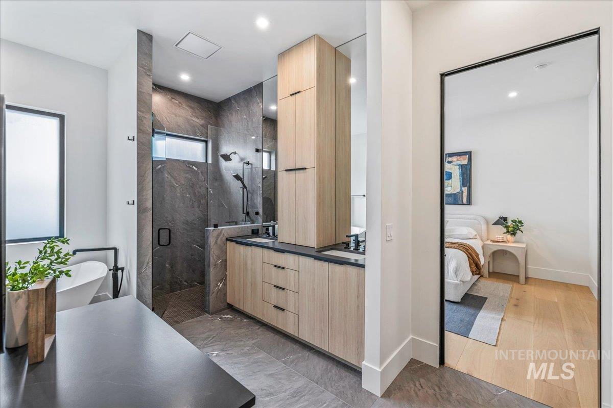 Ensuite bathroom with a marble finish shower, double vanity, a soaking tub, and recessed lighting