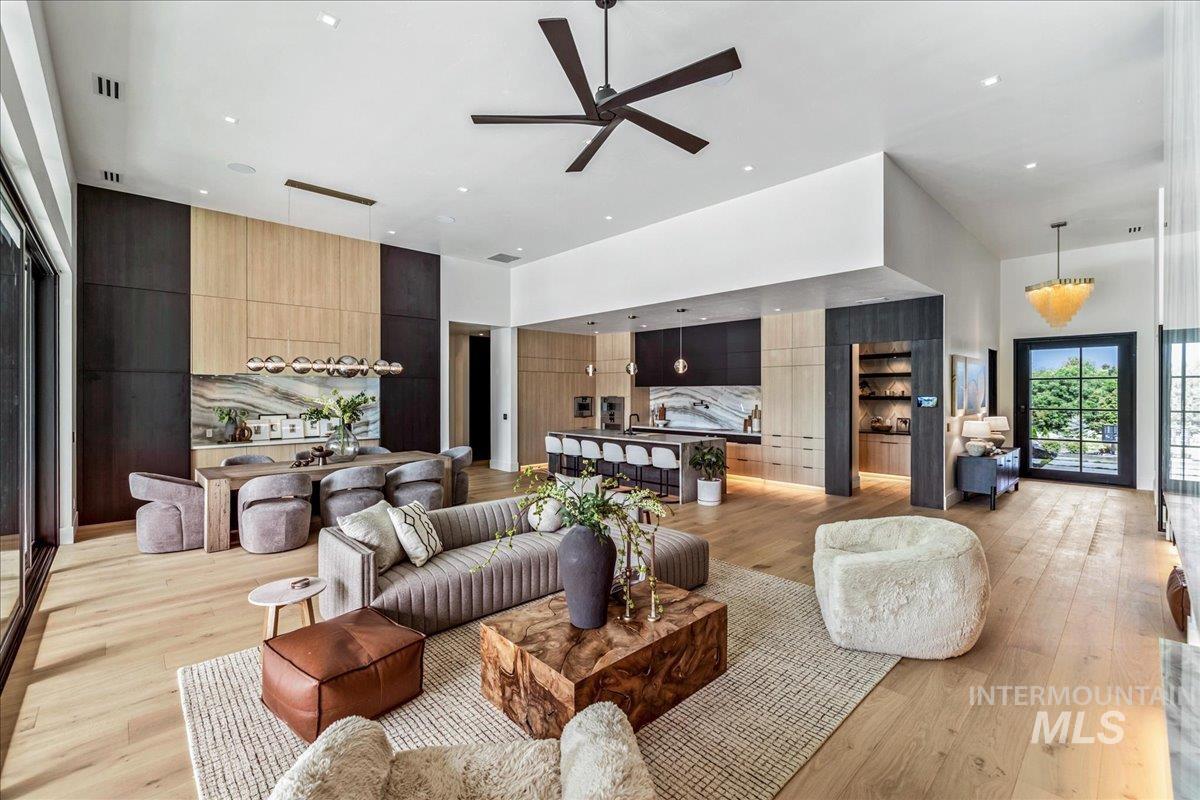 Living area with light wood-type flooring, a ceiling fan, a high ceiling, and recessed lighting