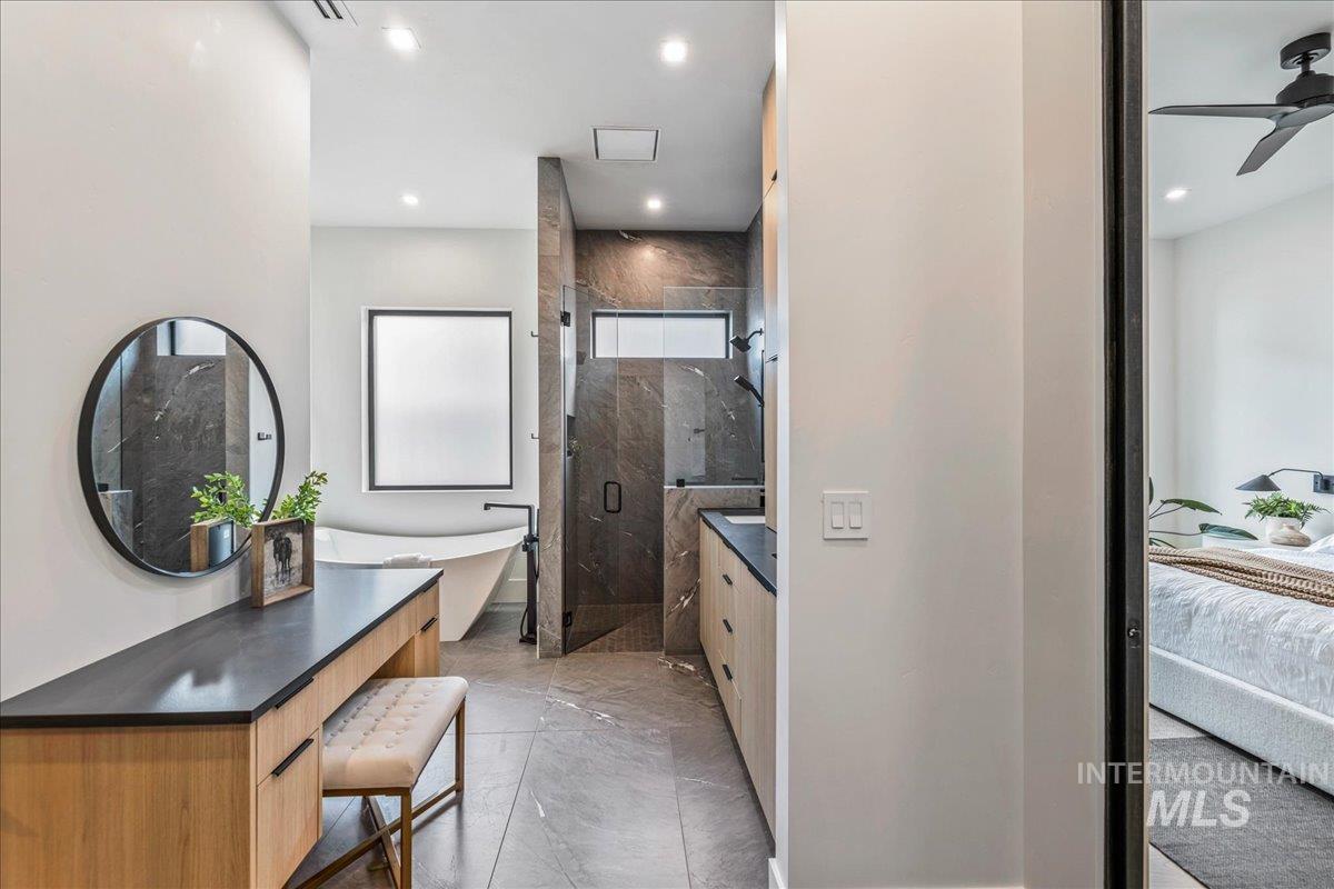 Ensuite bathroom featuring a marble finish shower, a freestanding tub, ceiling fan, recessed lighting, and vanity