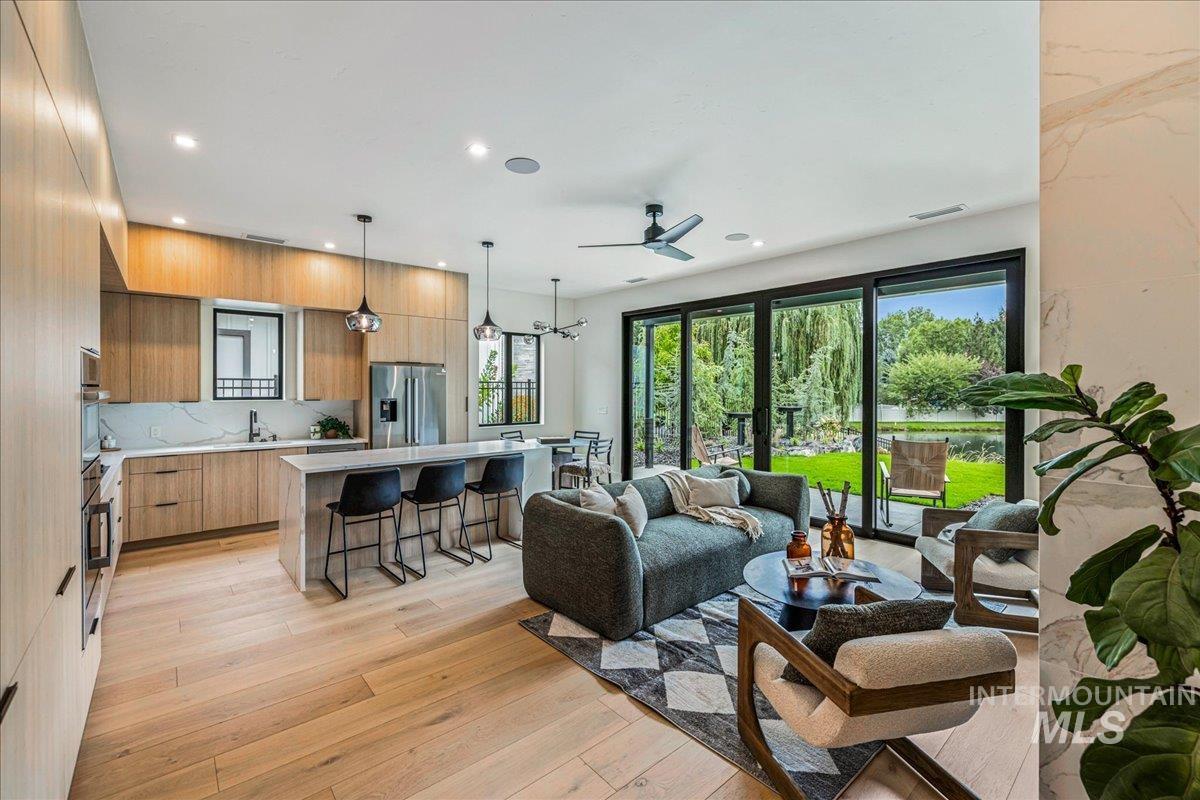 Living room featuring light wood-type flooring, ceiling fan, and recessed lighting