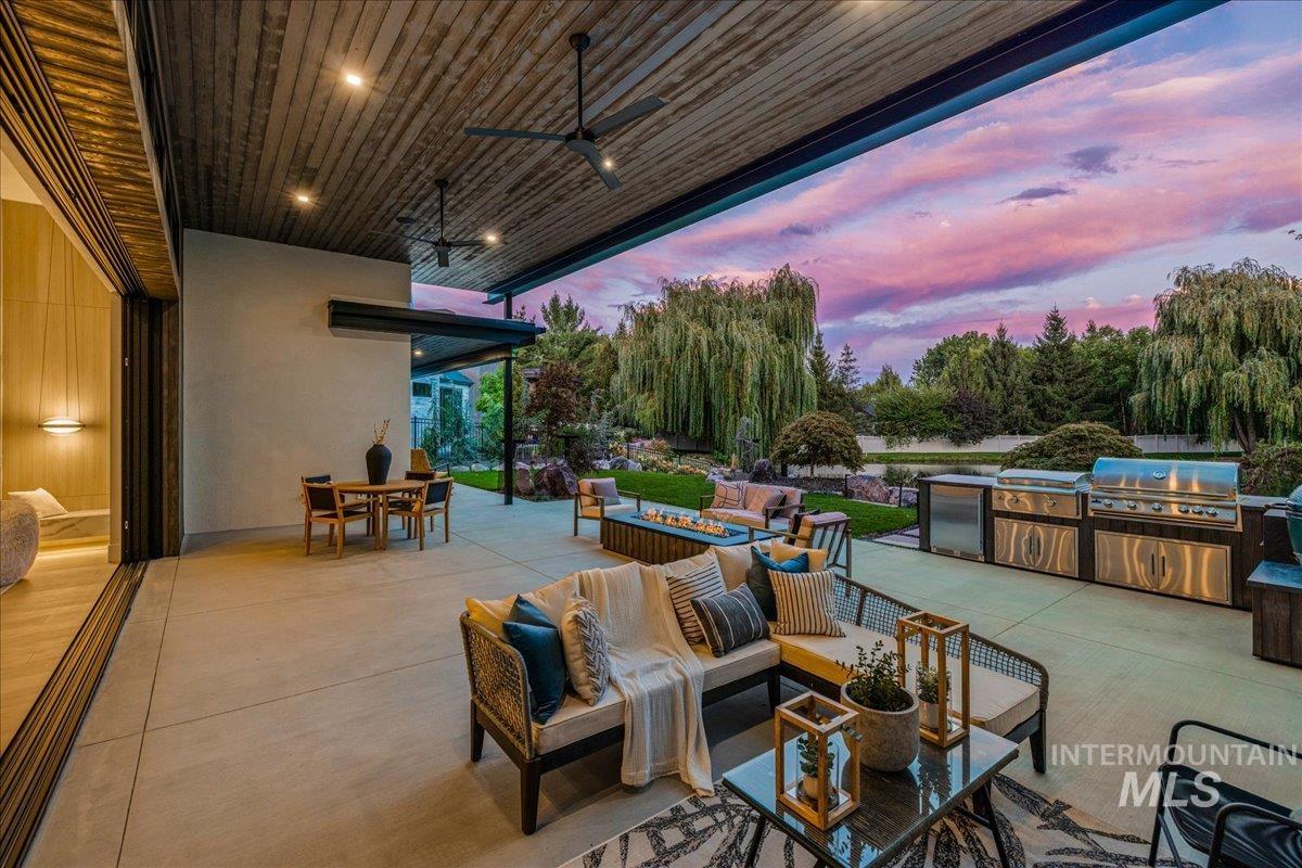 Patio terrace at dusk featuring an outdoor kitchen, a ceiling fan, outdoor dining area, an outdoor hangout area, and a patio