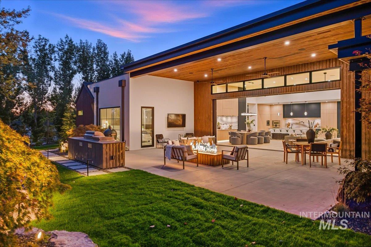 Back of house with a patio area, an outdoor living space, exterior kitchen, a lawn, and stucco siding