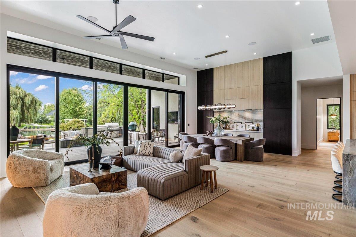 Living room featuring plenty of natural light, light wood-style floors, a high ceiling, recessed lighting, and ceiling fan