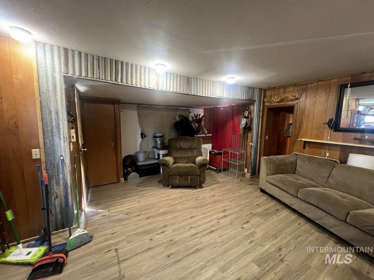 Living room featuring wooden walls, light wood-style flooring, and a textured ceiling