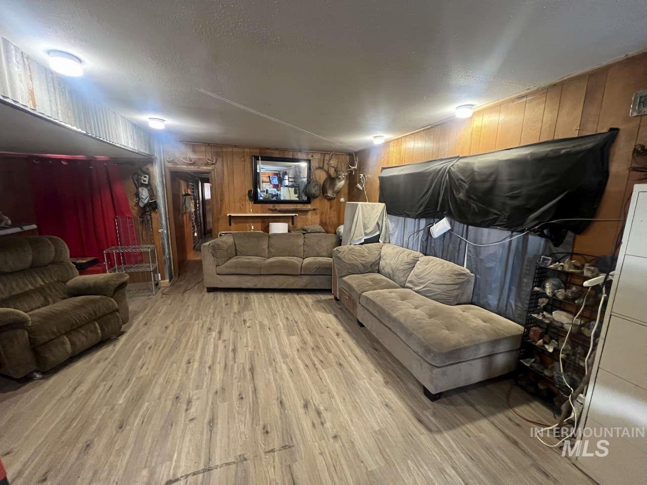 Living room with wooden walls, wood finished floors, and a textured ceiling