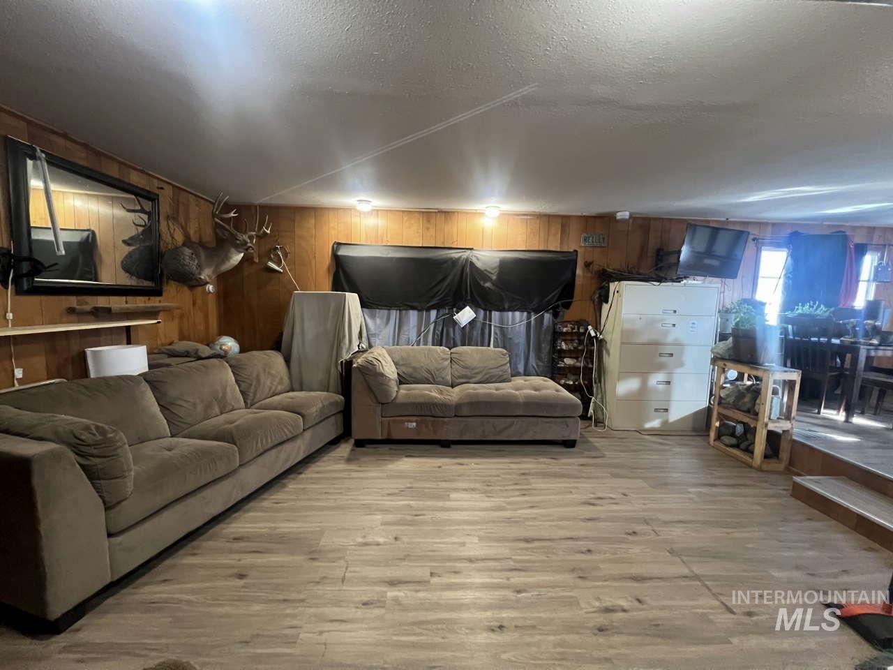 Living area with light wood-style floors, a textured ceiling, and wooden walls